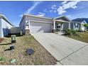 Single-Gathering home features a well-maintained front yard, attached garage, and front porch at 590 Tanaro Ln, Haines City, FL 33844