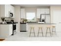 Modern kitchen with sleek, stainless-steel appliances, white cabinetry, gray countertops and a convenient center island with seating at 2899 Transformation Way, Clermont, FL 34714