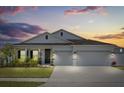 Elegant single-story home boasts lush landscaping and a spacious three-car garage at dusk at 921 Fieldstone Way, Haines City, FL 33844