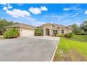 Beautiful single-story home features a two-car garage, archway entrance, and manicured landscaping with vibrant flowers and palm trees at 3979 Mammoth Grove Rd, Lake Wales, FL 33898