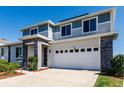 Attractive two-story home with stone accents, a two-car garage, and lush green landscaping on a bright day at 1123 Sugarwood St, Davenport, FL 33837