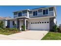 Charming two-story home with gray and white facade, stone accents, and well-maintained landscaping at 1123 Sugarwood St, Davenport, FL 33837