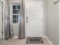 Bright entryway featuring a stylish front door, tiled floors, and elegant curtains at 6889 Wilson Hammock Ave, Groveland, FL 34736