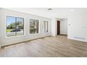 Bright living room featuring three large windows, wood-look flooring, and a solid wood front door at 2791 Citron Dr, Longwood, FL 32779