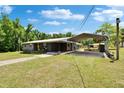 Wide angle shot of a gray brick home with a matching carport, surrounded by a spacious green lawn at 4145 Willow Oak Rd, Mulberry, FL 33860