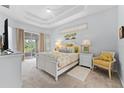 Bright main bedroom featuring a tray ceiling, neutral carpet and private balcony access at 6442 Bendelow Dr, Lakeland, FL 33810