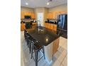 Spacious kitchen island features a dark countertop with bar seating and is surrounded by ample cabinetry at 153 Tigerlily Ct, Davenport, FL 33837