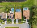 Aerial view of a home with a screened-in pool, bordered by lush greenery and a serene pond at 460 Tess Ct, Orlando, FL 32834