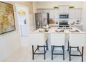 Modern kitchen featuring an island with seating, stainless steel appliances, and white cabinets at 5884 Meditation Dr, Clermont, FL 34714