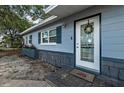 Close up of a charming single story home with blue painted wood siding and decorative wreath and welcome mat at 5932 Hilltop E Ln, Lakeland, FL 33809