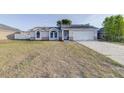 Traditional home with neutral color palette, two-car garage, arched windows, and an expansive front yard at 2769 Corrigan Dr, Deltona, FL 32738