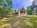 A-frame home with stone accents, balcony, and fenced yard, surrounded by mature trees and green grass at 2900 Cr 415, Lake Panasoffkee, FL 33538