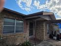 Home exterior featuring a brick facade, a covered entrance, and a well-lit walkway under a cloudy blue sky at 115 Marjorie Ave, Auburndale, FL 33823