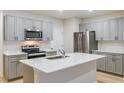 Modern kitchen with grey cabinets, stainless steel appliances, and an island with quartz countertop at 3775 King Hill Dr, Haines City, FL 33844