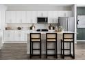 Bright and modern kitchen featuring white cabinetry, stainless steel appliances, a large center island, and stylish bar stools at 4027 Gardenia Ave, Lake Hamilton, FL 33851
