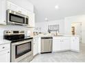 Well-lit kitchen boasts stainless appliances, sleek white cabinetry, and stone countertops at 800 Reggie Rd, Winter Haven, FL 33884