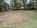 Spacious backyard, partially grassed, with shade trees and a wood fence in the distance at 2212 Ne 11 Ct, Ocala, FL 34470