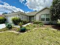 Close-up view of front yard of single-story home with a well-manicured lawn and garden at 11928 Se 91St Cir, Summerfield, FL 34491