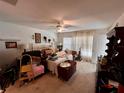 Cluttered main bedroom with carpeted floors, ceiling fan, curtains, and standard closet at 11928 Se 91St Cir, Summerfield, FL 34491