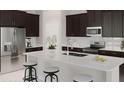 Modern kitchen features a large island with seating, stainless steel appliances, and dark wood cabinetry at 5431 Lewisham Dr, Davenport, FL 33837