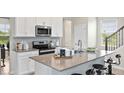 Modern kitchen featuring stainless steel appliances, white cabinets, and a large island at 2437 Spring Tune Aly, Kissimmee, FL 34744