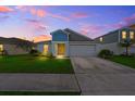 Inviting home at dusk features manicured lawn, attached garage, and warm interior lighting at 5933 Slate Rock Dr, Lakeland, FL 33811