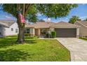 Well-maintained single-story home with a paver driveway, attached garage, and manicured front lawn with mature trees at 9345 Se 171St Le Flore Ln, The Villages, FL 32162