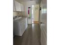 Functional laundry room with white cabinets and a washing machine next to the entry hallway at 9345 Se 171St Le Flore Ln, The Villages, FL 32162
