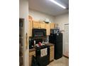 Condo kitchen with black refrigerator and appliances, and wood cabinetry at 12849 Madison Pointe Cir # 204, Orlando, FL 32821
