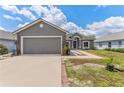 Charming gray home with a two-car garage, lush lawn, driveway, landscaped walkway, and inviting front entrance at 181 Osprey Heights Dr, Winter Haven, FL 33880