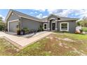 Charming gray home with a two-car garage, lush lawn, landscaped walkway, and inviting front entrance at 181 Osprey Heights Dr, Winter Haven, FL 33880