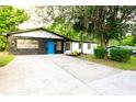 Charming home with stone accents, a vibrant blue door, and mature trees creating a welcoming entrance at 808 S Clara Ave, Deland, FL 32720