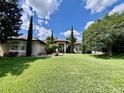 Inviting home featuring a manicured lawn, lush landscaping, and a stately entrance with white columns at 16325 Magnolia Bluff Dr, Montverde, FL 34756