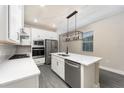 Modern kitchen featuring white cabinets, stainless steel appliances, gray wood flooring, and a kitchen island with pendant lighting at 7661 Somersworth Dr, Kissimmee, FL 34747