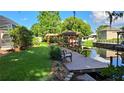 Beautiful backyard with a waterfront view and a wooden dock with a gazebo and a bench at 12430 Blue Heron Way, Leesburg, FL 34788