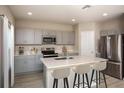 Modern kitchen features gray cabinetry, stainless steel appliances, and a large island with bar seating at 1617 Sage Ave, Haines City, FL 33844