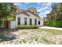 Side view of a charming two-story home featuring stucco siding, a tile roof, arched windows, and manicured landscaping at 952 Moss Ln, Winter Park, FL 32789