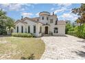 Charming two-story home featuring stucco siding, a tile roof, arched windows, and a brick driveway at 952 Moss Ln, Winter Park, FL 32789