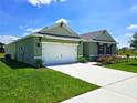 Green single-story home with a two-car garage, driveway, well-manicured lawn, and landscaped garden at 3148 Caspian Feather St, Bartow, FL 33830