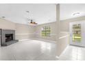 Spacious living room with a brick fireplace, tile floors, a ceiling fan, and a large window for natural light at 3331 Lime Tree Dr, Edgewater, FL 32141