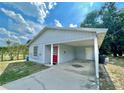 Charming single story home featuring a red front door, covered parking, and small front yard at 1310 Payne St, Auburndale, FL 33823