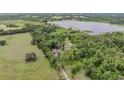 Expansive aerial shot showcases a home with outbuildings nestled amongst trees with a well-maintained lawn and lake nearby at 1611 County Road 753S, Webster, FL 33597