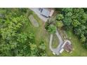 Overhead view features a home, pond, and an outbuilding with parking all connected by a winding driveway on a tree-filled lot at 1611 County Road 753S, Webster, FL 33597