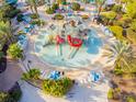 Aerial view of a resort water park with pools, slides, palm trees, and lounge chairs surrounding a water play area at 7523 Excitement Dr, Kissimmee, FL 34747