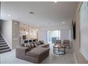 Spacious living room featuring a modern sectional sofa, stylish decor, and sliding doors to the outdoor area at 1430 Reunion Blvd, Reunion, FL 34747