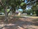 Spacious front yard showing the home's exterior with mature trees, outbuildings, and ample parking space at 2220 Woods Trl, Lakeland, FL 33809