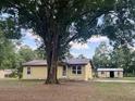 Charming single-story home with a metal roof, nestled on a large lot with mature trees and a storage shed at 2220 Woods Trl, Lakeland, FL 33809