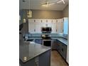 This open kitchen offers gray and white cabinets, a stainless steel range and granite countertops at 938 Oxford Way, Lake Wales, FL 33853