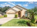 Charming single-story home with a brick driveway, two-car garage, and manicured landscaping with palm tree at 908 Andalusia Loop, Davenport, FL 33837