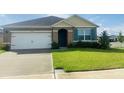A single-story home with a two car garage, a well maintained lawn, and a tidy landscape design at 3974 Mekong Ct, St Cloud, FL 34772